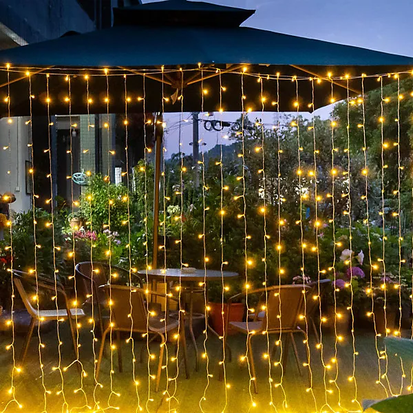 Solar curtain string lights hanging over a garden dining area at night